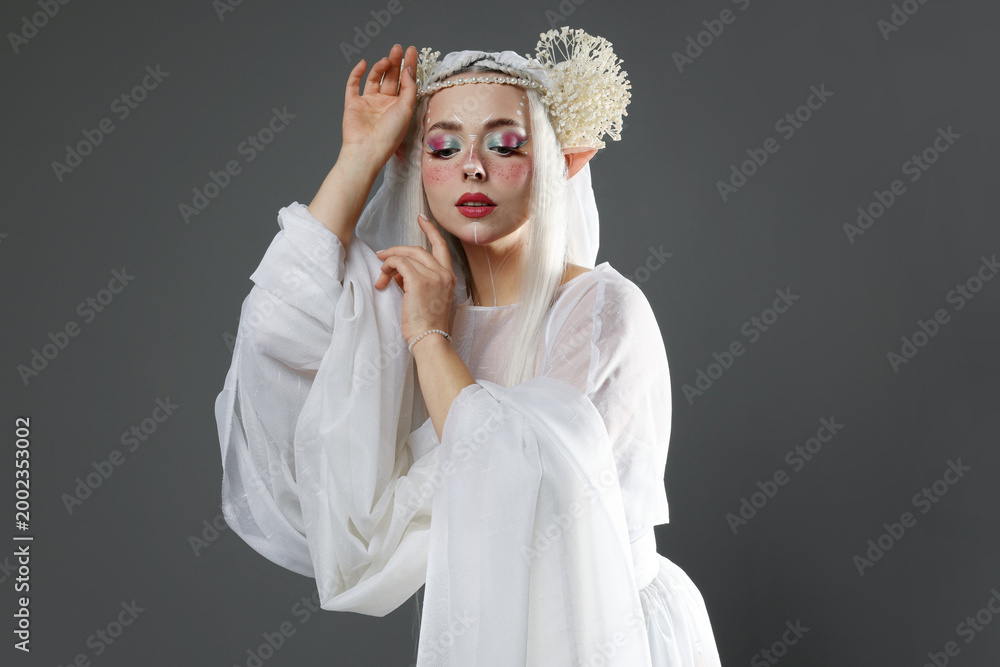 Fototapeta premium Beautiful girl dressed as elf on grey background