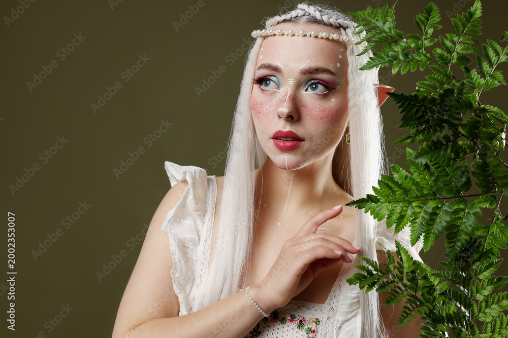 Fototapeta premium Beautiful elf girl with floral decor on dark olive background, space for text
