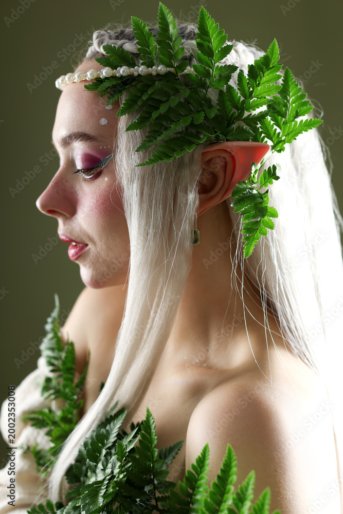 Fototapeta premium Beautiful elf girl with floral decor on dark olive background