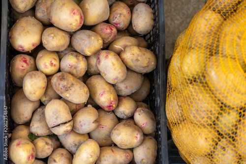 Quadro su tela Fresh raw potatoes in crate and mesh bag