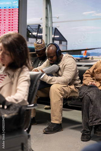 Fotografía Man on holiday trip listening to music, waiting in airport lounge during delayed flights