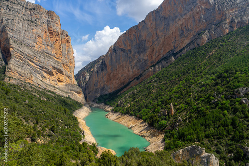 Turquoise reservoir in dramatic limestone canyon with forested slopes