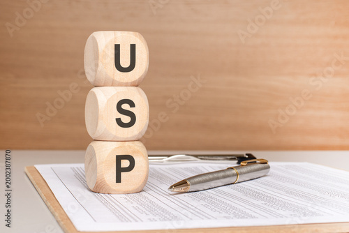 Wooden blocks stack with USP Unique Selling Proposition business marketing concept, pen, and documents.