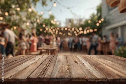 A wooden table overlooks a blurred outdoor gathering illuminated by string lights.