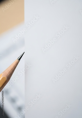 Sharp Pencil Tip Pointing at Blank White Paper with Copy Space