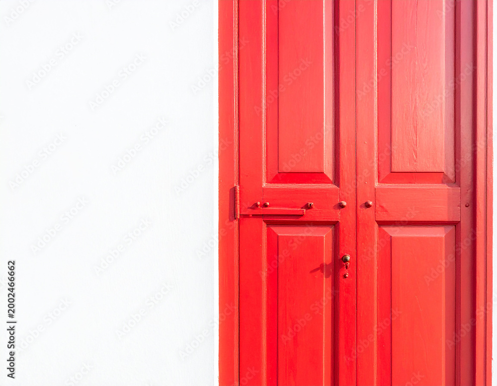 Obraz premium Bright red double doors with metal hardware against a stark white wall with a subtle texture