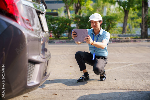 Insurance agent inspecting car damage after accident