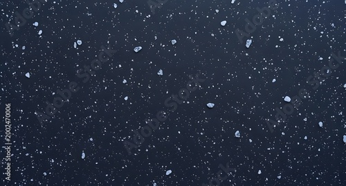 Beautiful image of falling snowflakes against a dark winter night sky, capturing the serene and magical atmosphere of snowfall, cold weather, and winter wonderland scenery.