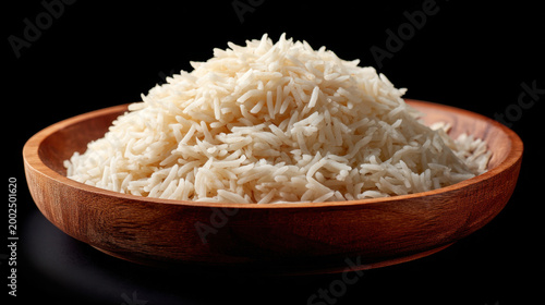 Plain rice in wooden bowl isolated on black background, side view of white grain food with simple rustic serving dish