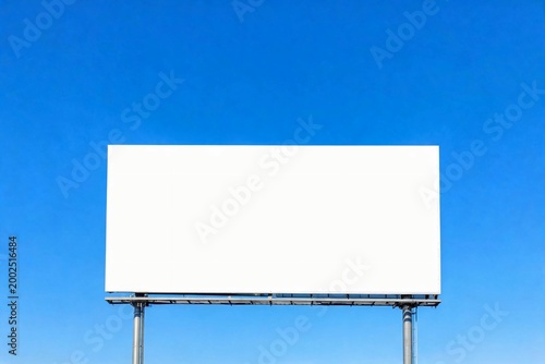 White billboard stands tall against clear blue sky.