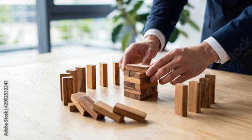 Bild auf Leinwand Hands carefully construct a new structure from wooden blocks, symbolizing business recovery and strategic rebuilding