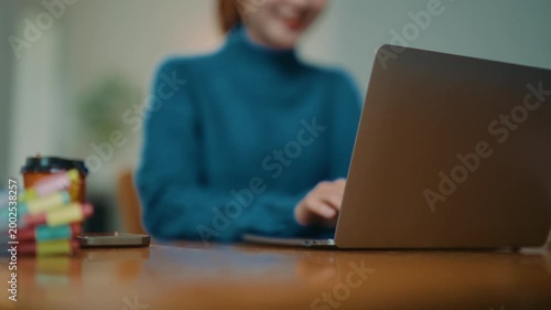 Happy Asian businesswoman working on her laptop at home office. Smiling freelancer using computer for online work or studying