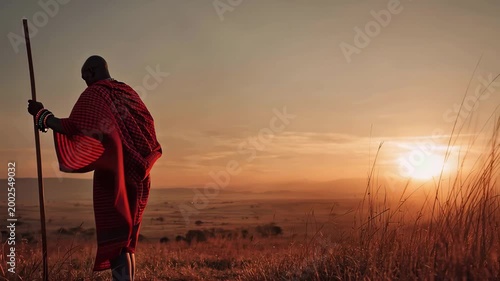 Maasai warrior walks towards the sunset in traditional red shuka and beadwork on the plains of Africa during evening