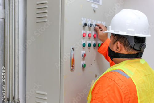 Canvas-taulu Industrial worker in hard hat adjusting control panel in factory