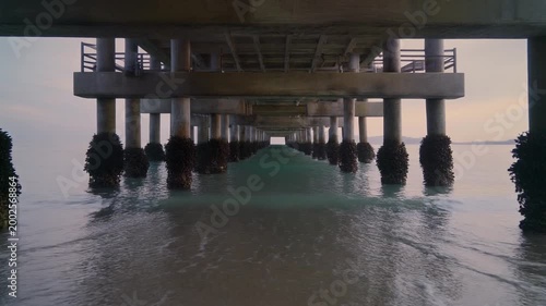 Pier Perspective: A captivating view beneath a pier as gentle waves meet the textured pillars, leading the eye into an unending horizon. Generative AI.