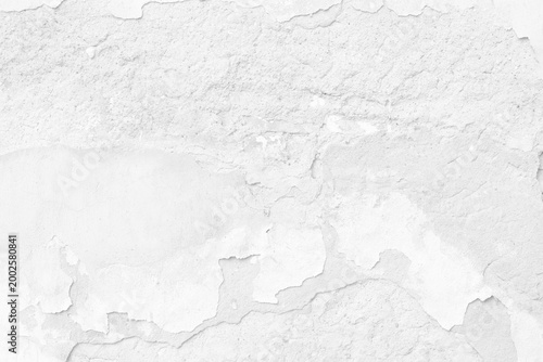 Close-up of peeling white paint texture on an aged concrete wall with weathered flaking surface