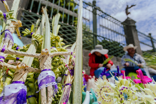 фотографія Close-up of Jesus Christ figures woven from palm leaves, with artisans selling their crafts outside a church during Holy Week