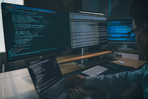 Developing programmer Website design at a multi monitor workstation with laptop and screens displaying scripts, showing web development, coding, software workflow, and technical productivity in dark o