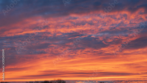 Vivid orange and pink sunset sky with dramatic textured clouds