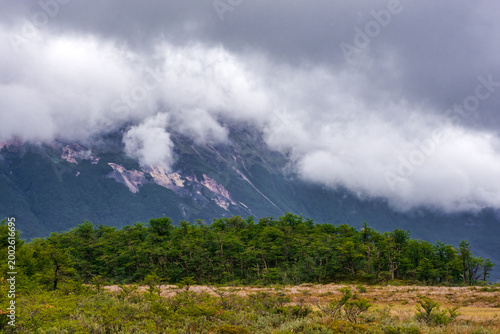 Dramatic mountain peaks partially hidden by mist and low clouds in Tierra del Fuego