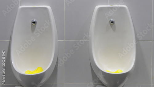 Foto White urinals side by side against tiled wall