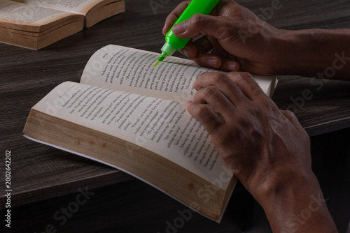 Принти на полотні Close-up of a person's hands studying and highlighting text on open book pages w