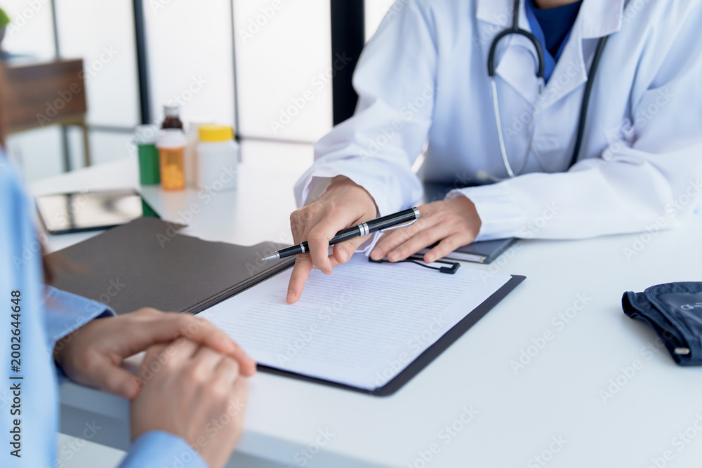 Fototapeta premium Doctor explaining treatment plan and obtaining informed consent while patient signing consent form in hospital.
