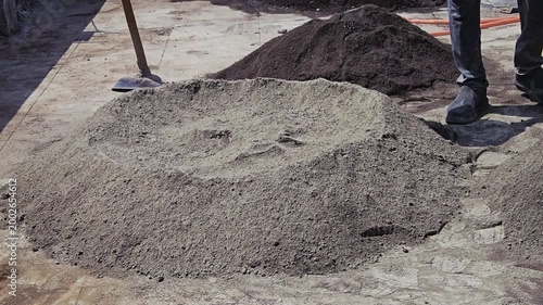 Workers manually mix sand and cement into a uniform dry mix on a clean surface. This traditional hand-mixing technique is ideal for small batches of concrete or mortar before water is finally added.