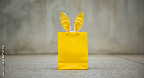 Yellow Easter bag with bunny ears on concrete