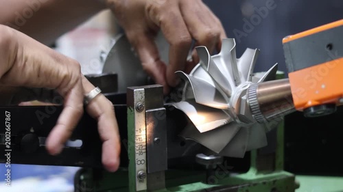 Close up of a mechanic hands setting up a metal turbine shaft on a precision dynamic balancing machine for technical maintenance in an industrial automotive workshop.