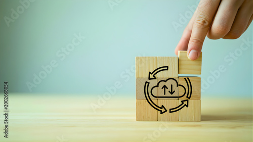 Hand places a wooden block with cloud data transfer icon, illustrating technology integration and seamless synchronization for efficient business solutions and digital transformation