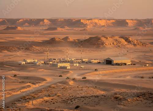 Israeli military base in desert landscape with sandy hills and rugged rock formations at sunset