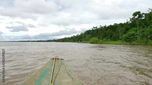 POV wooden boat ride on Amazon River near Iquitos Peru along rainforest shoreline smooth travel footage