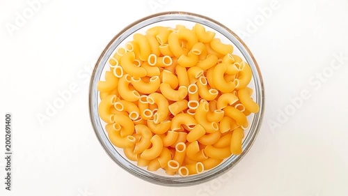 Elbow Macaroni Pasta in Glass Bowl Rotating on White Background, Uncooked Elbow Macaroni Pasta Ingredient