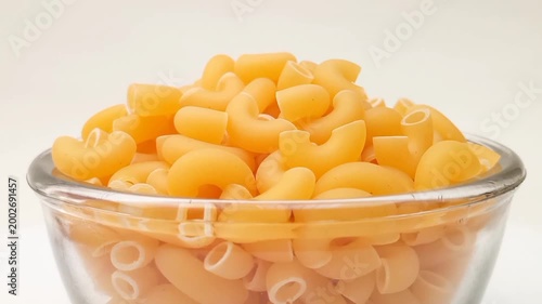 Elbow Macaroni Pasta in Glass Bowl Rotating on White Background, Uncooked Elbow Macaroni Pasta Ingredient