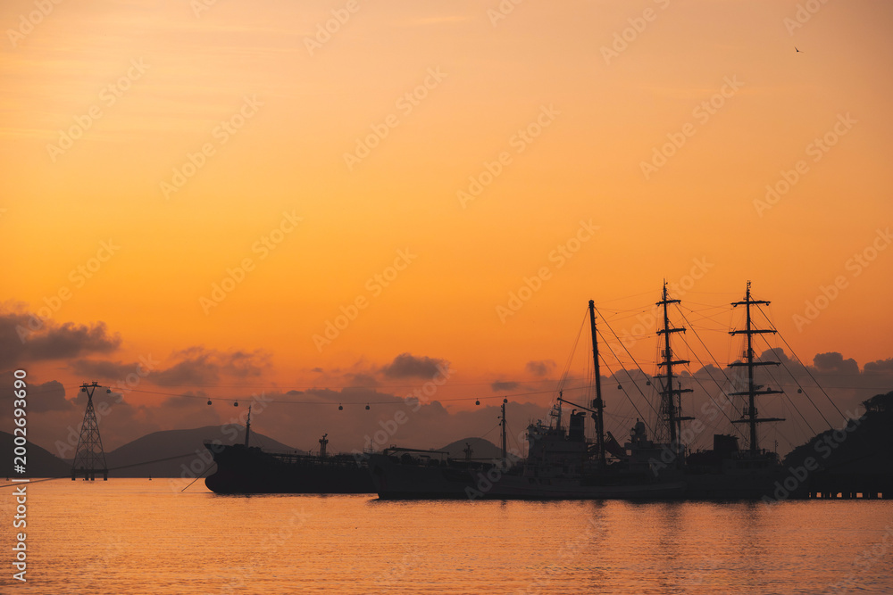 Fototapeta premium Silhouettes of Vietnamese warships military ships in port at sea in morning at sunrise in harbor in Nha Trang in Vietnam