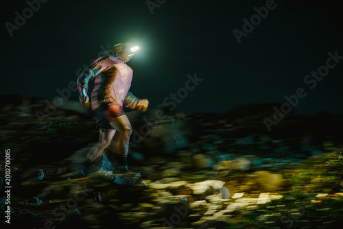 Fotografie Motion blur of an athlete trail running in the dark with a headlight