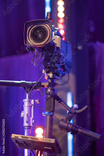 Vertical view of professional broadcast video camera on tripod in studio with copy space