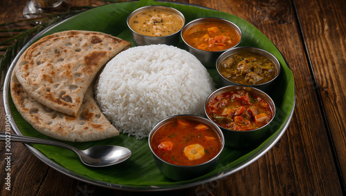 South indian rice and curry meal on banana leaf with main course