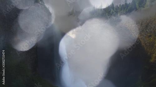 Foreground droplets shifting and merging from spray, slowly revealing waterfall and canyon walls