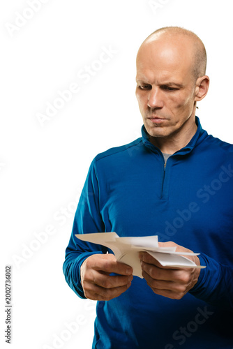 Man reading receipts with worried look, vertical portrait showing furrowed brow and focused gaze, conveying personal finance concern, bill reconciliation and careful cost review