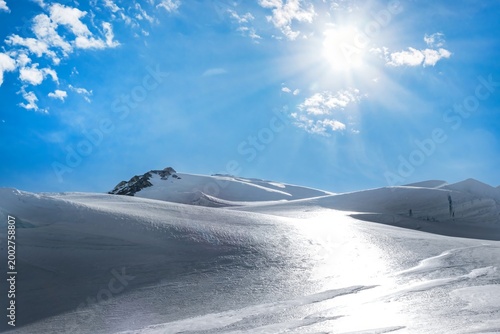 Bild auf Leinwand Sunlight over pristine glacier landscape with snow covered alpine peaks