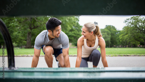 Playful couple abandoning a serious sprint drill to turn their outdoor workout into a spontaneous, flirtatious racing game.