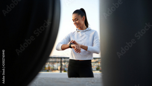 Self-motivated runner finding quiet satisfaction in her training data during a solitary cooldown moment.