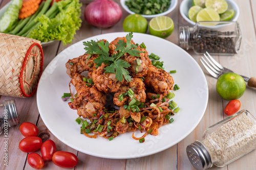 фотографія Spicy minced chicken on a white plate complete with cucumber, lettuce and side dishes