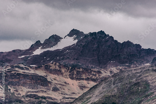 High Andean peaks covered in snow under a heavy gray overcast sky in southern Argentina.