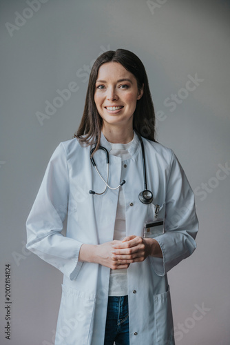 Scientist in lab coat with stethoscope smiling indoors at workplace