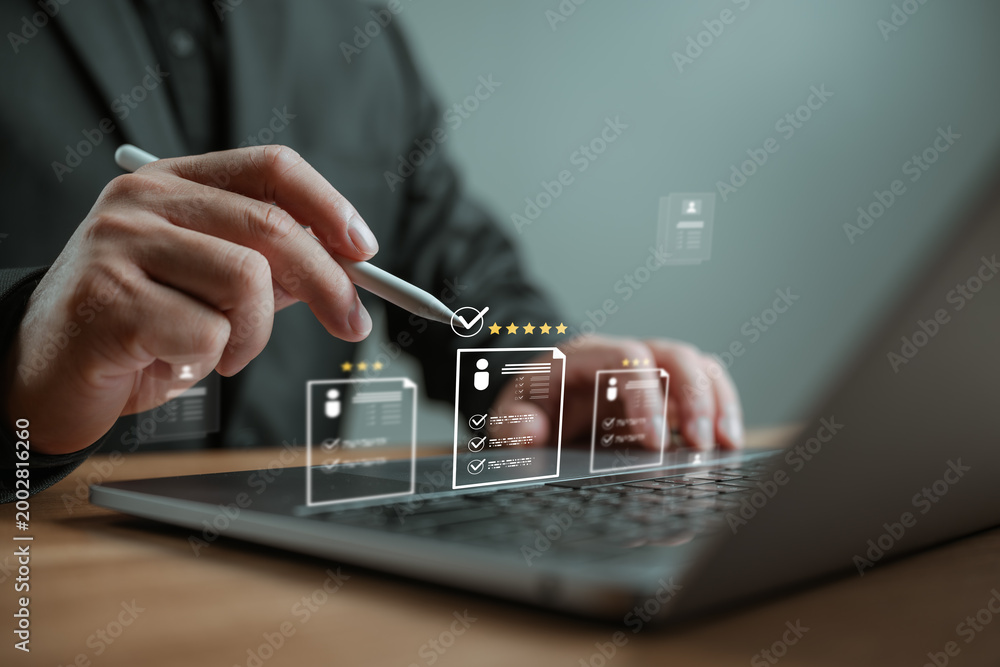 Obraz premium Businessman using laptop to select best candidate resume with star rating. Concept of human resources management, online recruitment, digital hiring process, and talent acquisition technology.