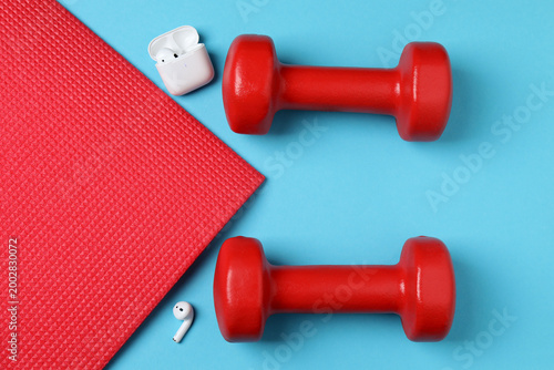 Obraz na płótnie Stylish dumbbells, measuring tape and rubber band on blue background