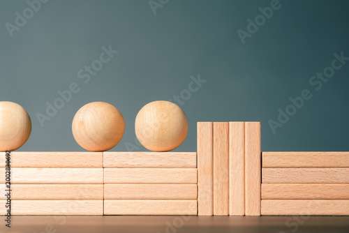 Bottleneck concept, smooth wooden pathway blocked by vertical barrier causing accumulation and congestion of moving elements, representing limited capacity and workflow slowdown
